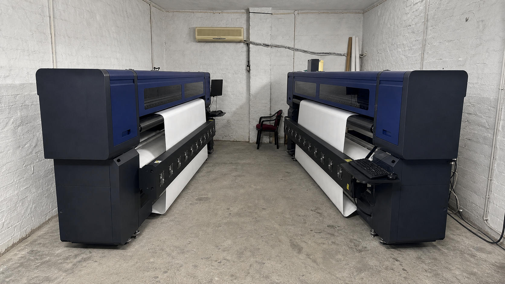 Two digital printing machines with white material mounted on rolls