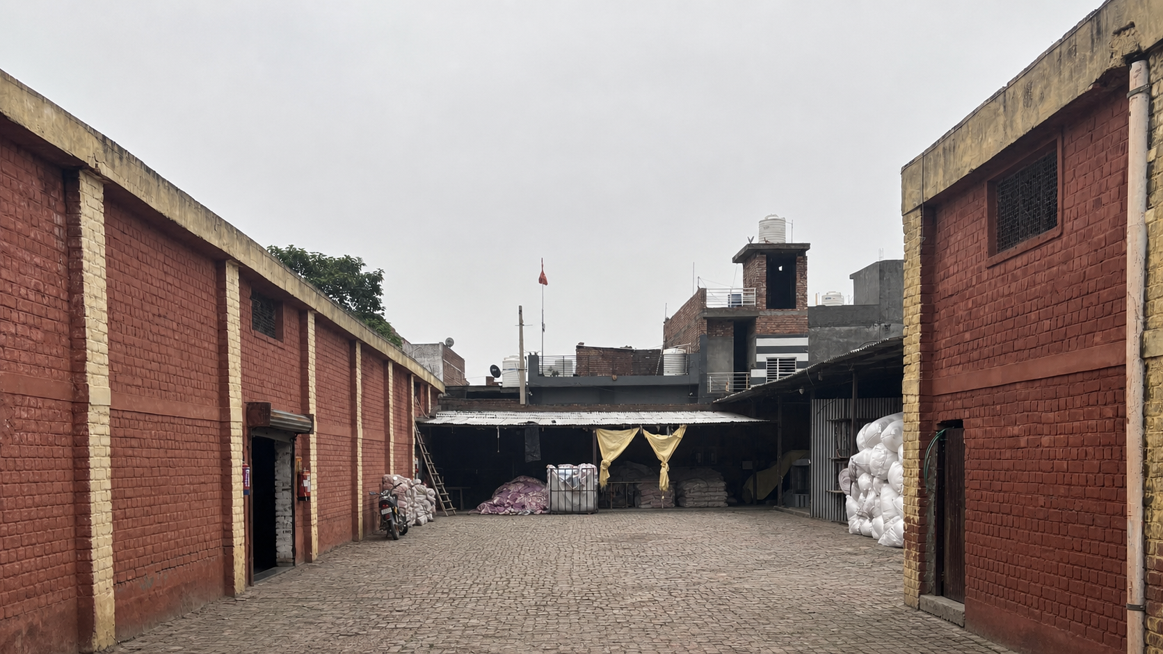 Brick warehouse buildings around the loading yard, with bundled materials at the far end
